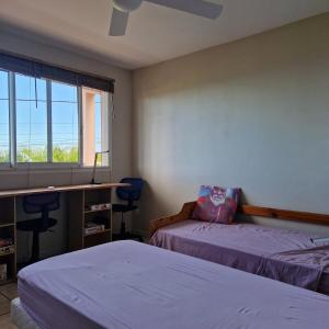 ein Schlafzimmer mit zwei Betten und einem Schreibtisch und einem Fenster in der Unterkunft Petit jardin suspendu in Petite Île