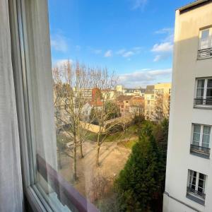 een raam met uitzicht op een park en gebouwen bij A spacious room in a strategic area in Montrouge