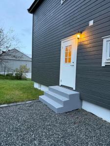 a house with a white door and stairs on it at Nyoppusset leilighet til leie in Isfjorden