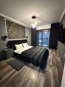 een slaapkamer met een bed en een groot raam bij Tampa Gardens Apartments - Adults Only in Braşov