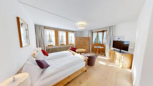 een woonkamer met een bed en een televisie bij Schweizerhaus Swiss Quality Hotel in Maloja