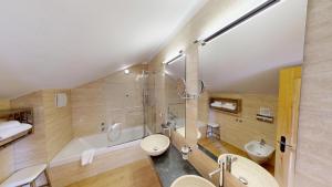 een badkamer met toilet, wastafel en bad bij Schweizerhaus Swiss Quality Hotel in Maloja +43 foto's