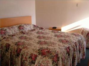 a bedroom with a bed with a floral bedspread at Motel Six in Hamilton