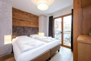 a bedroom with a large white bed and a window at Mountain Lodge Leogang-Premium Apartment, Balkon, Bergblick, Kamin, Sauna in Leogang