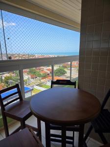 een tafel en stoelen in een kamer met een groot raam bij Beachfront Apartment in Itanhaém