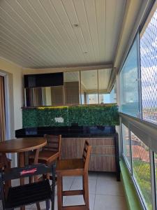 een balkon met een tafel en stoelen en een groene muur bij Beachfront Apartment in Itanhaém