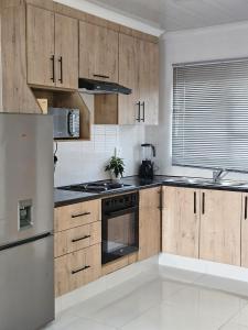 a kitchen with wooden cabinets and a stainless steel refrigerator at KLAAK hotel and Apartments in Ga-Masamothane