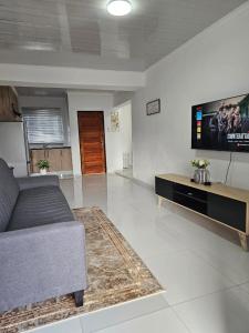 a living room with a couch and a flat screen tv at KLAAK hotel and Apartments in Ga-Masamothane