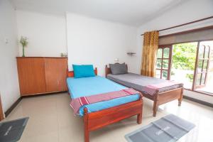 una camera da letto con due letti singoli e una finestra di The Spring Holiday a Mirissa