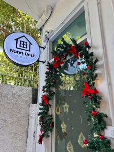 una finestra con ghirlande natalizie e un cartello sopra di Nana Best Hostel a Makkasan