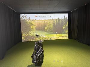 a golf equipment in a room with a large screen at Siggjo Guesthouse Bømlo and Stord in Mosterhamn