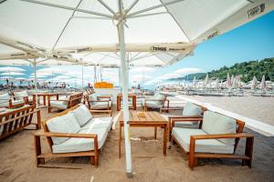 een groep stoelen en tafels met een parasol op het strand bij Hotel Harmonia by Dukley in Budva