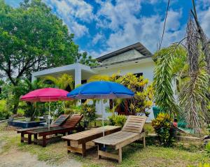 a group of benches and umbrellas in front of a house at In Dream Villa in Rekawa