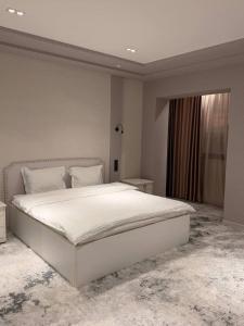 OktyabrʼGrand Hotel的卧室里有一张白色的大床，床边有一扇窗户