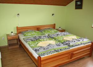 a bedroom with a wooden bed with green and white sheets at Chata Dominika - Tále in Bystrá