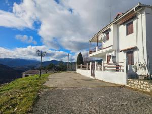 a white building on a hill next to a street at Portitsa View Guesthouse in Spílaion