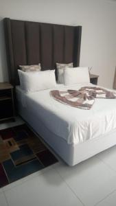 a bed with white sheets and pillows in a room at KLAAK hotel and Apartments in Ga-Masamothane
