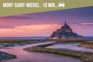 een foto van een kasteel op een heuvel naast een rivier bij Aux Berges Du Mont - Parking, 10 min Mont-Saint-Michel & Jardin in Pontorson