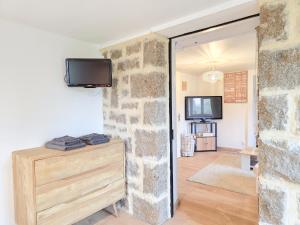 een woonkamer met een stenen muur en een tv bij Aux Berges Du Mont - Parking, 10 min Mont-Saint-Michel & Jardin in Pontorson