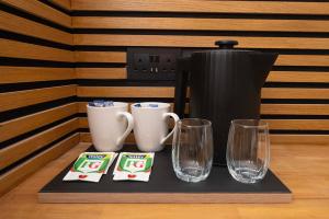 ein Tablett mit Tassen und Gläsern auf einer Kaffeemaschine in der Unterkunft Amber Hotel Double Room in Hull