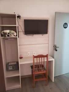 een kamer met een bureau, een televisie en een stoel bij Hotel leo in Pelotas
