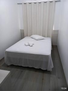 een slaapkamer met een wit bed en een wit gordijn bij Hotel leo in Pelotas