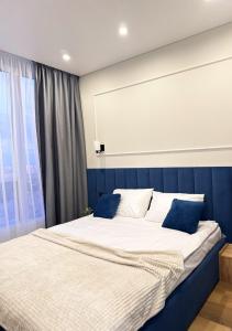 een slaapkamer met een groot bed met een blauw hoofdeinde bij New Business-Class Apartament з генератором Varshavsky Retroville in Kiev +46 foto's