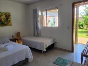 ein weißes Zimmer mit zwei Betten und einem Fenster in der Unterkunft Pousada Canto das Estrelas in Chapada dos Guimarães