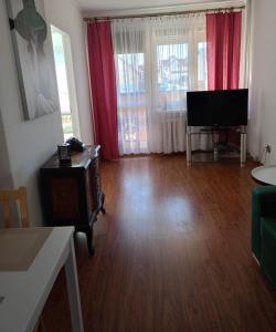 a living room with a television and red curtains at Hel - Apartament in Hel