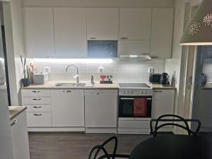 a kitchen with white cabinets and a sink and a stove at Huoneisto järvinäkymin, Palokka in Jyväskylä