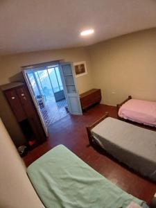 een slaapkamer met twee bedden en een deur naar een kamer bij La Casona Hostel CUENTA OFICIAL in Bermejo