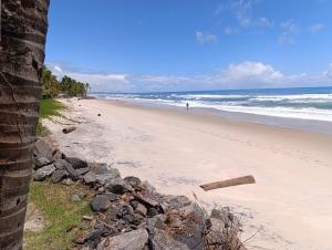 a beach with a person walking in the ocean at Divas do mar kitnet 7 in Ilhéus +10 photos