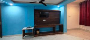 a room with a tv on a blue wall at Hotel Gloria Rishikesh in Rishīkesh