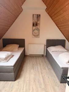 due letti in una stanza con pavimenti in legno di Zentrale Erbendorfer Studiowohnung a Erbendorf