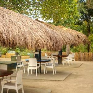 a patio with chairs and tables and a straw umbrella at Happy Laugh Ella in Ella