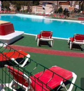ein Schwimmbecken mit zwei rot-weißen Stühlen in der Unterkunft Meloneras Maspalomas Pasito Blanco in Pasito Blanco