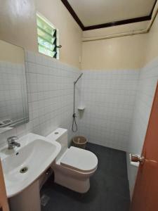 a bathroom with a white toilet and a sink at CocoVille Guesthouse Barkada Room in Alegria