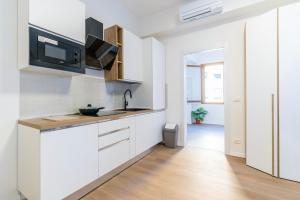 a kitchen with white cabinets and a tv on the wall at Ipin Home in Mestre +29 photos