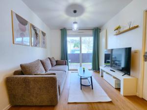 a living room with a couch and a tv and a table at Le Silvestre in Bouliac