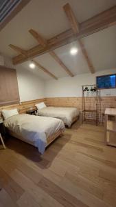 two beds in a large room with wooden floors at Hakuba Icicle House in Hakuba