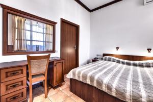 een slaapkamer met een bed, een bureau en een stoel bij Спа Хотел Орфей in Devin