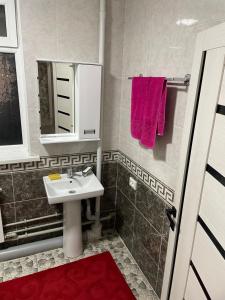 een badkamer met een wastafel en een spiegel bij Nur Hotel in Karakol