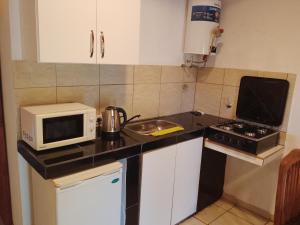a small kitchen with a microwave and a stove at Depto Calamuchita Rumipal in Villa Rumipal +1 photo