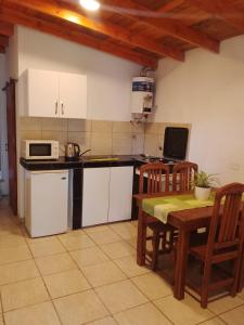 eine Küche mit weißen Schränken und einem Tisch mit Stühlen in der Unterkunft Depto Calamuchita Rumipal in Villa Rumipal