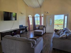 a living room with two couches and a flat screen tv at Cozy Hill Vista in Micoud