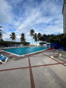 a large swimming pool with palm trees in the background at Son de Metro Apartment - Condado Beach & Pool, Walk to Ocean in San Juan