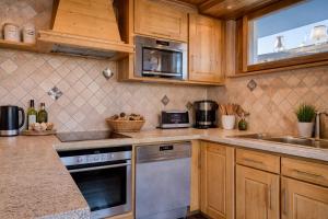 een keuken met houten kasten en roestvrijstalen apparatuur bij Appartements dans le Chalet Nessa - Combloux in Combloux