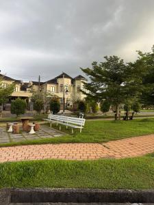 a park with a white bench and trees and houses at The Luxe Stay in Kuching