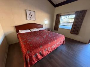 een slaapkamer met een bed met een rood dekbed en een raam bij Royal inn in Quincy