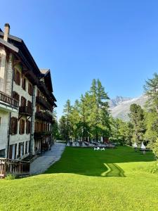 un edificio con un cortile erboso accanto a una montagna di Grand Hôtel & Kurhaus ad Arolla